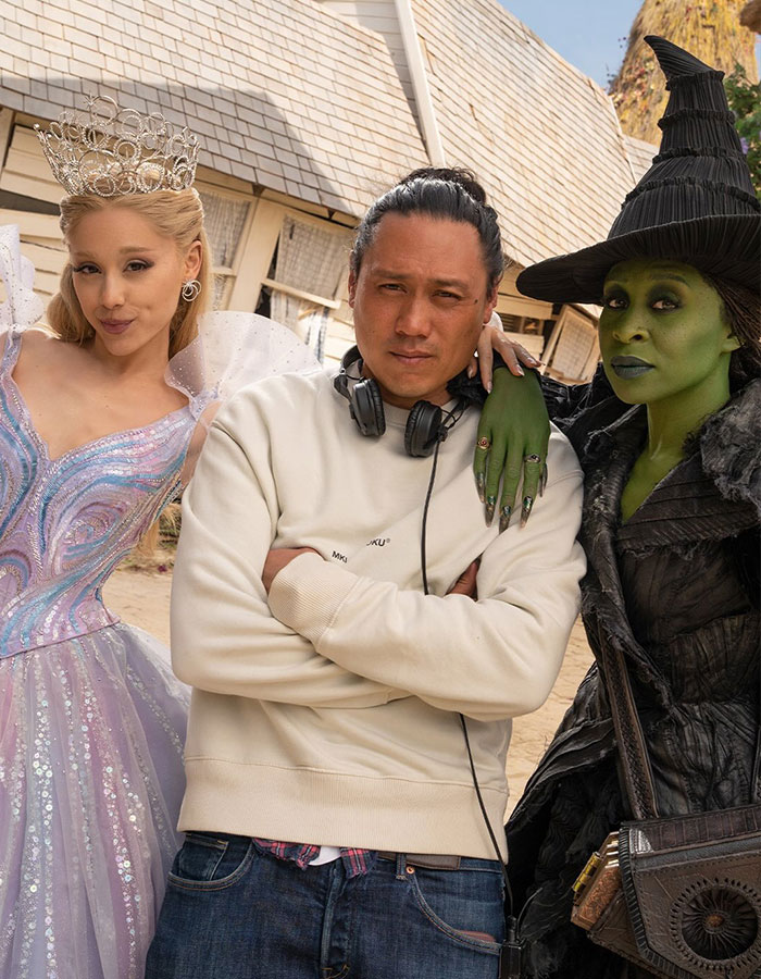 Cynthia Erivo in green witch makeup and a man with headphones between her and a woman in a sparkling princess dress. Cynthia Erivo in green witch makeup and a man with headphones between her and a woman in a sparkling princess dress.