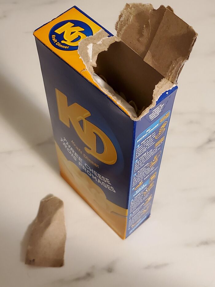 Opened Kraft Dinner box with torn cardboard lid showing small design mistakes in packaging design.