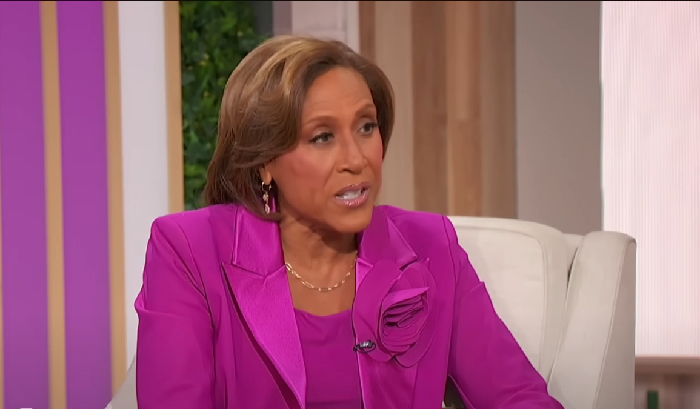 Robin Roberts in a purple suit discussing rare conditions on a daytime talk show set during an interview session.
