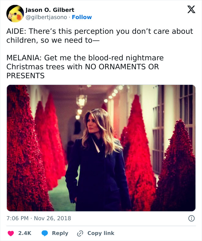 Melania Trump standing near blood-red Christmas trees, related to her controversial new Christmas ornament cost debate.