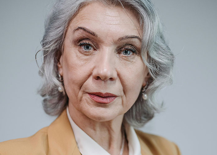 Close-up portrait of an older woman with gray hair, reflecting the shock of unhinged things said by MIL.
