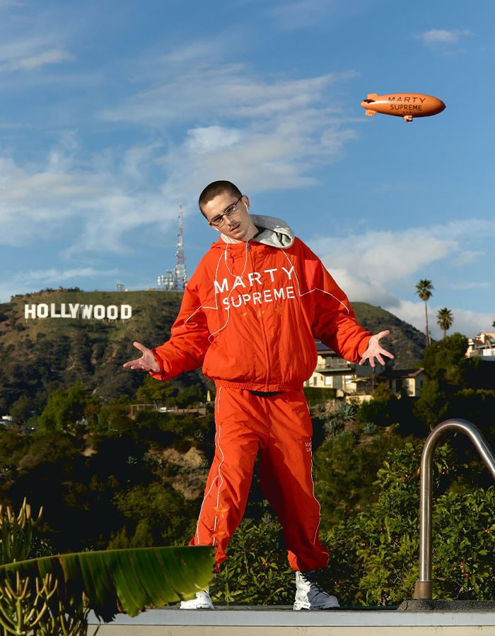 Man in red tracksuit posing near Hollywood sign under blue sky during daytime, reflecting Timothée Chalamet arrogance controversy. Man in red tracksuit posing near Hollywood sign under blue sky during daytime, reflecting Timothée Chalamet arrogance controversy.