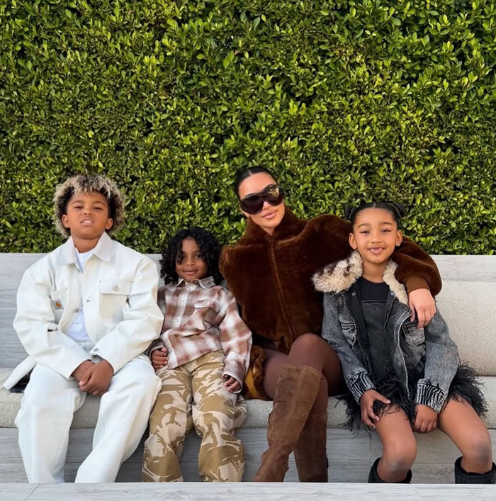 Kim Kardashian sitting with her kids outdoors, amid fans' reactions linking Christmas card failure to kids' home life.