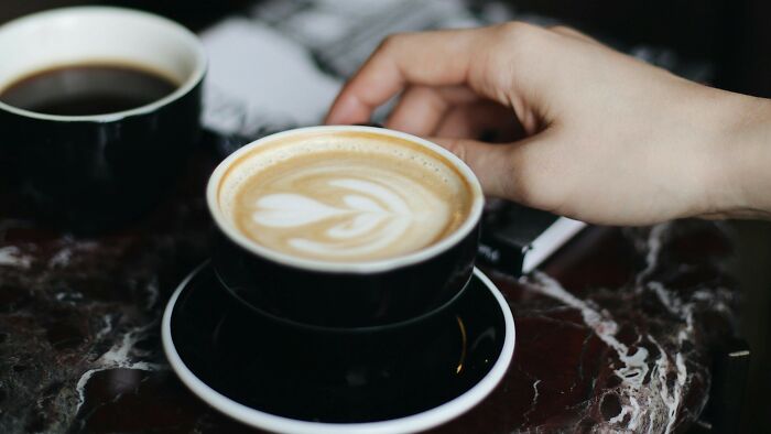 Hand reaching for a cup of coffee on a marble table, illustrating ambiguous situations for fault and right judgment.