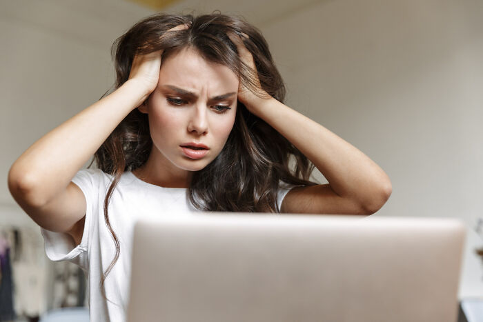 Young woman frustrated while looking at a laptop, illustrating crazy things people do believing their ex will always pine for them.