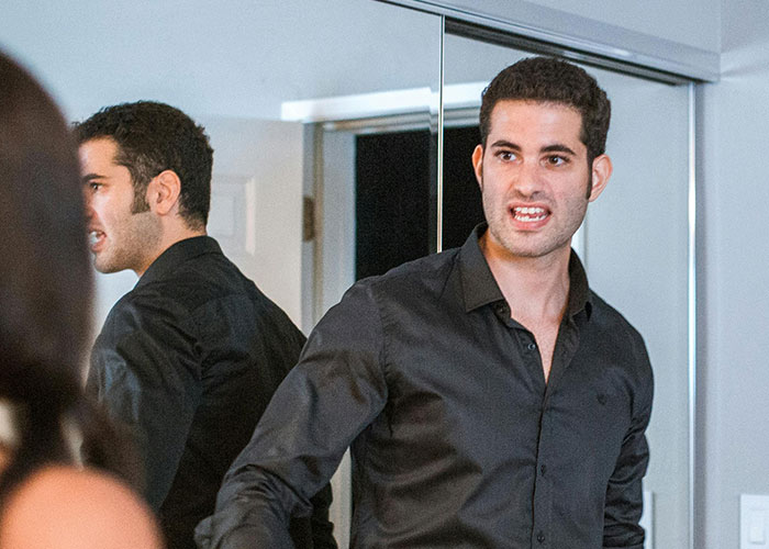 Man in a black shirt expressing anger in front of a mirror, illustrating wild stories about insane things exes have done