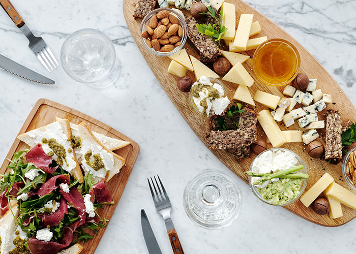 Luxury food platter with cheese, nuts, and greens served on wooden boards, highlighting luxury industries and rip-offs.