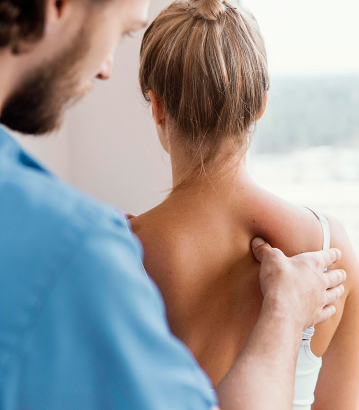 Doctor examining woman’s back during medical checkup, illustrating embarrassing moments recalled in front of doctors.