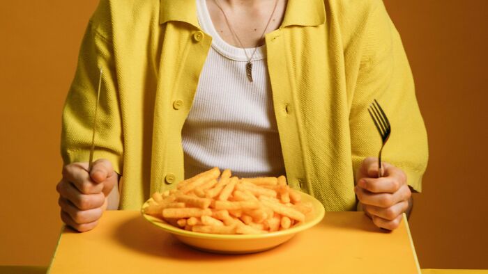 Person in yellow shirt holding fork and knife ready to eat snacks, illustrating fault and right ambiguous situations.