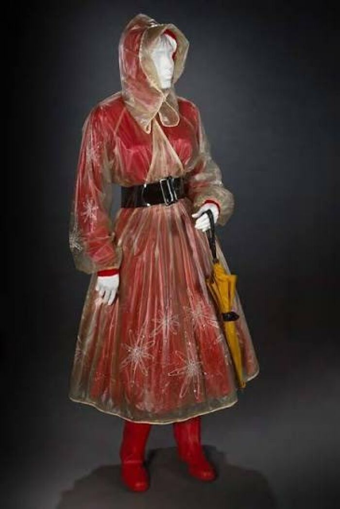Vintage fashion outfit with transparent raincoat, red dress, boots, and umbrella capturing culture in powerful old photos.