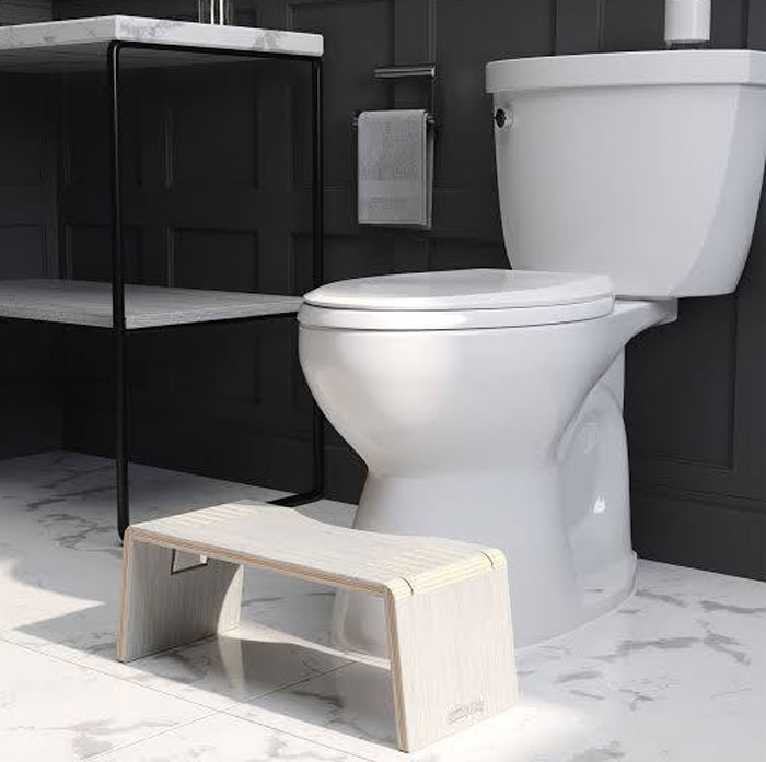 White elephant gifts perfect for stealing include a modern bathroom stool placed in front of a white toilet on marble tile.