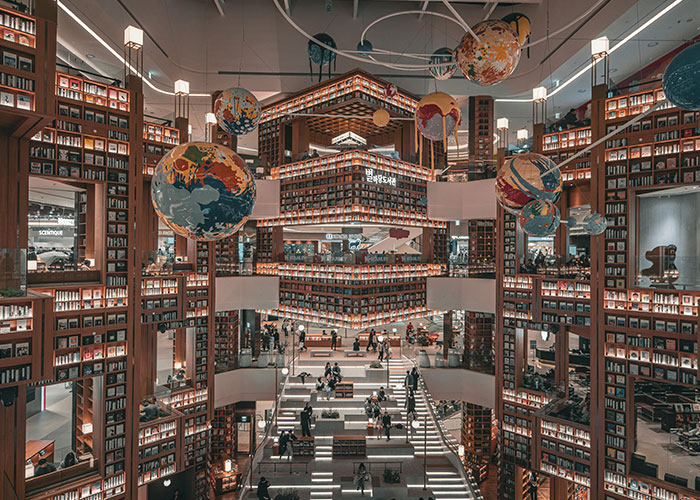 Spacious modern library with suspended colorful globes and towering bookshelves, a place that looks AI generated but is real.