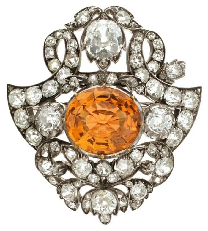 Antique brooch with a large orange gem surrounded by diamonds, showcasing culture and emotion in powerful old photos.