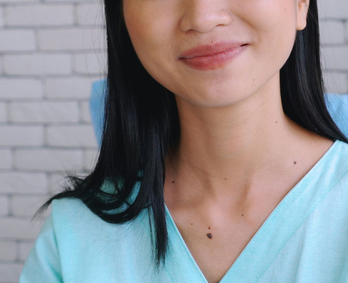 Young woman with slight smile sitting in clinic setting recalling embarrassing moments in front of doctors.