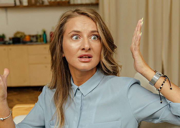 Woman in a blue shirt looking shocked and confused, illustrating reactions to unhinged things their MIL just said to them.