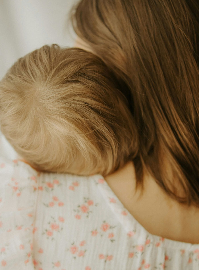 Close-up of a little kid resting on a parent's shoulder, capturing a tender moment with families and spicy roasts.