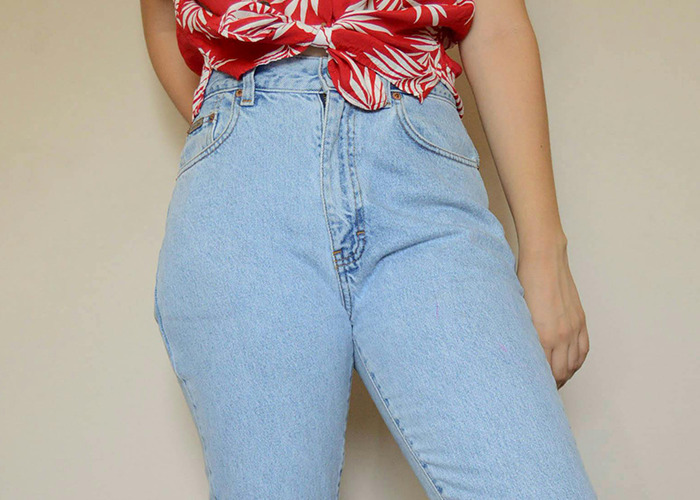 Person wearing high-waisted light blue jeans and a red and white patterned top, illustrating 911 operators dumbest non-emergency calls.