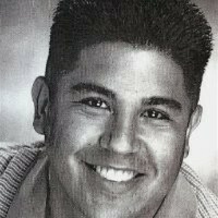 Black and white close-up of dad of Nickelodeon star Tylor Chase smiling in an indoor setting with short dark hair.