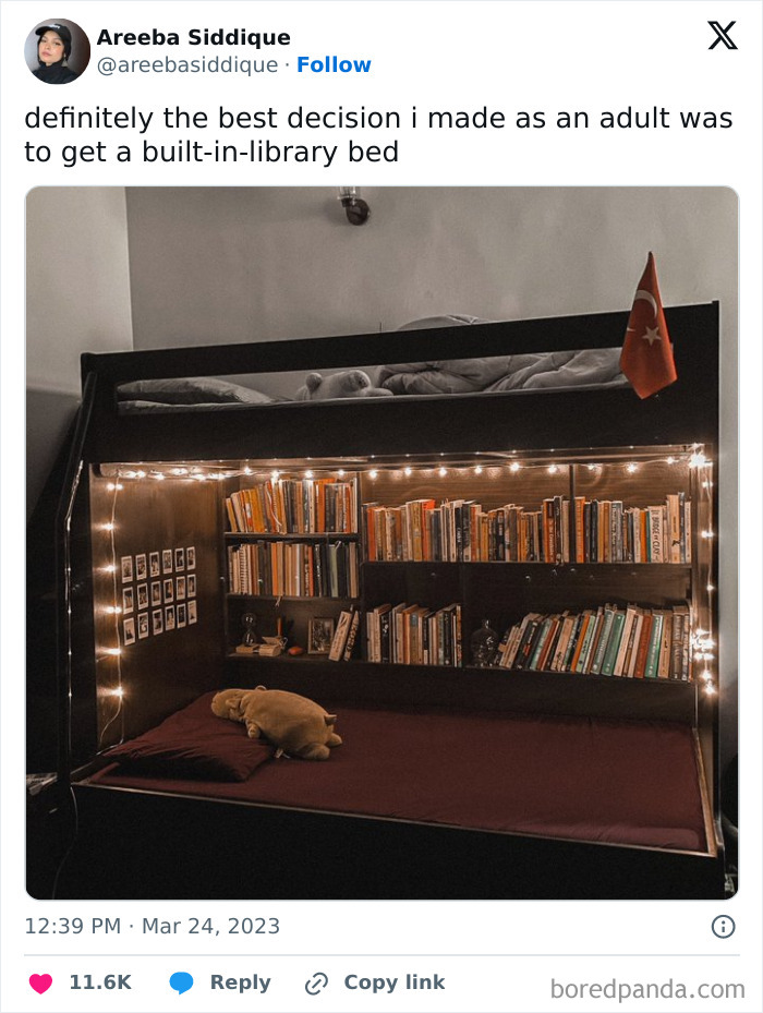 Cozy built-in-library bed with warm string lights, books neatly arranged, and a plush toy on a maroon mattress for a leap of faith.