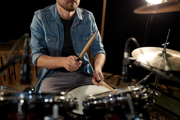 Man playing drums in a studio, showcasing the passion behind a once-famous regular job in music performance.