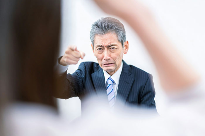Hombre de negocios señalando con enojo durante un escándalo en oficina que sacudió el ambiente laboral.