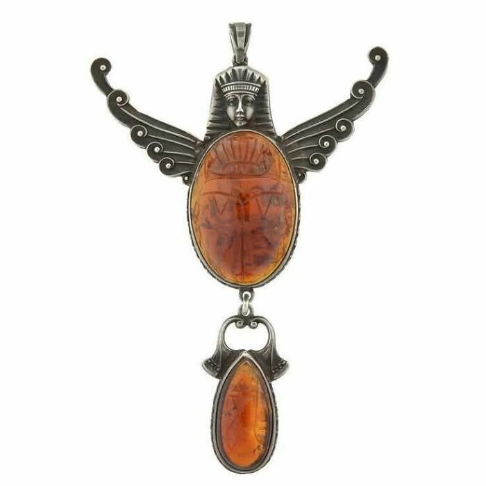 Vintage pendant with amber stones and an ancient carved figure, showcasing culture and emotion from the past.