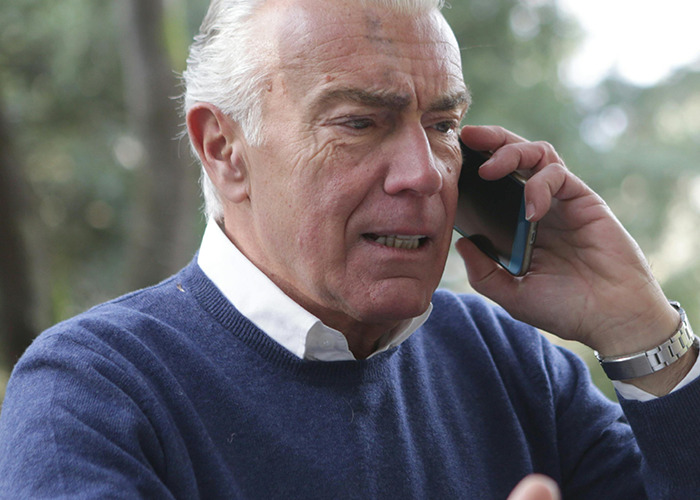 Elderly man looking concerned while talking on mobile phone, illustrating 911 operators handling non-emergency calls.