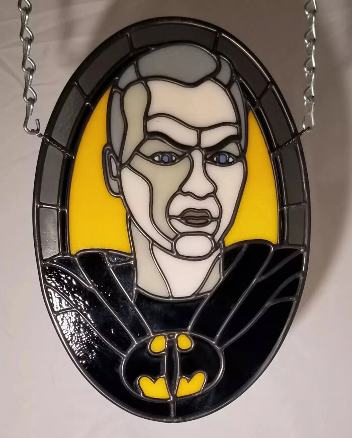 Stained glass sign featuring a pop culture icon with vivid colors and detailed design hanging by chains.