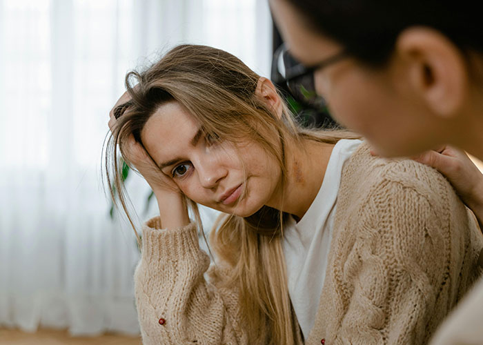Young woman looking distressed while another person offers comfort, illustrating shocked reactions to unhinged MIL comments.