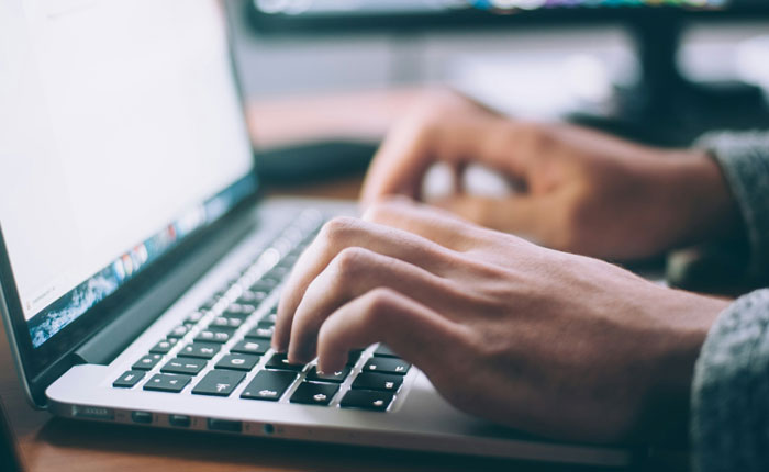 Person typing on a laptop keyboard, illustrating office scandals that caused sudden firings and workplace turmoil.