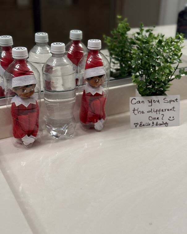 Elf on the Shelf hiding inside water bottles in a bathroom with a note challenging to spot the different one.