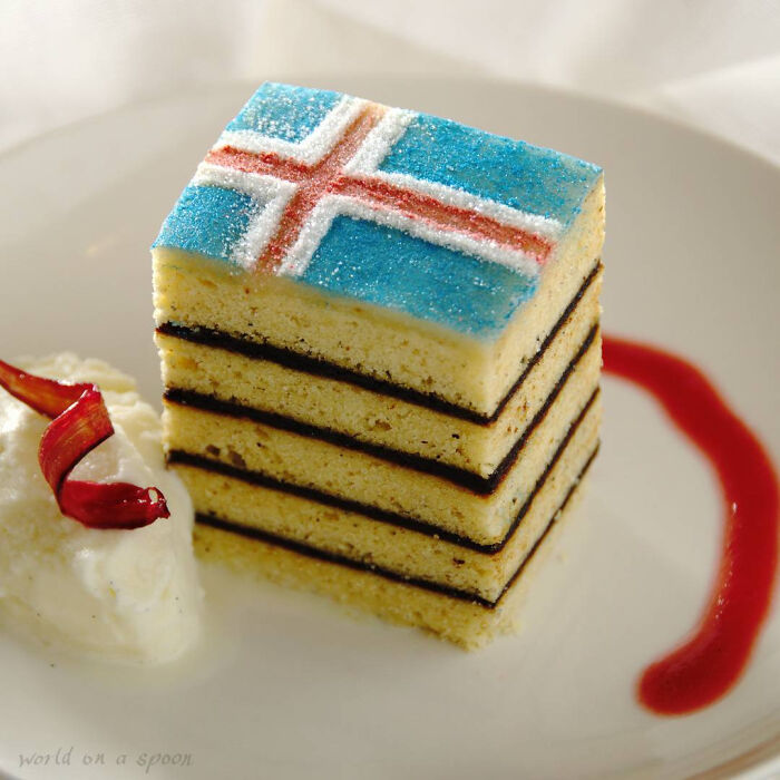 Layered Christmas dessert with Icelandic flag decoration served with cream and red sauce, showcasing Christmas desserts from around the world.