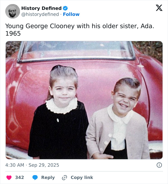 Young George Clooney with his sister Ada in 1965, sharing a heartfelt family moment by a red vintage car.