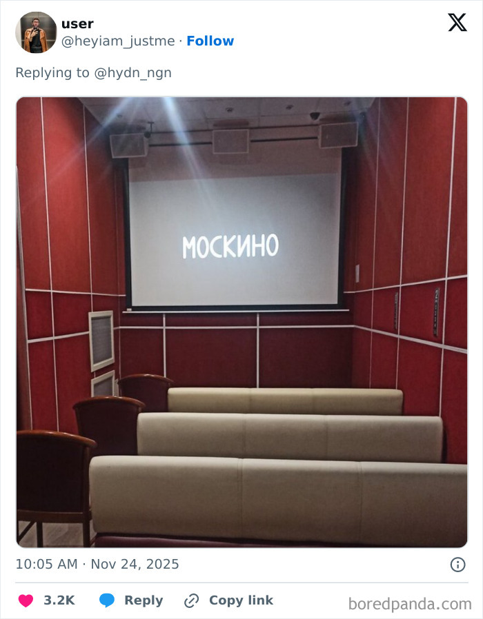 Small movie theater with old couches and red walls showing a movie screen, illustrating worst movie theaters shared by people.