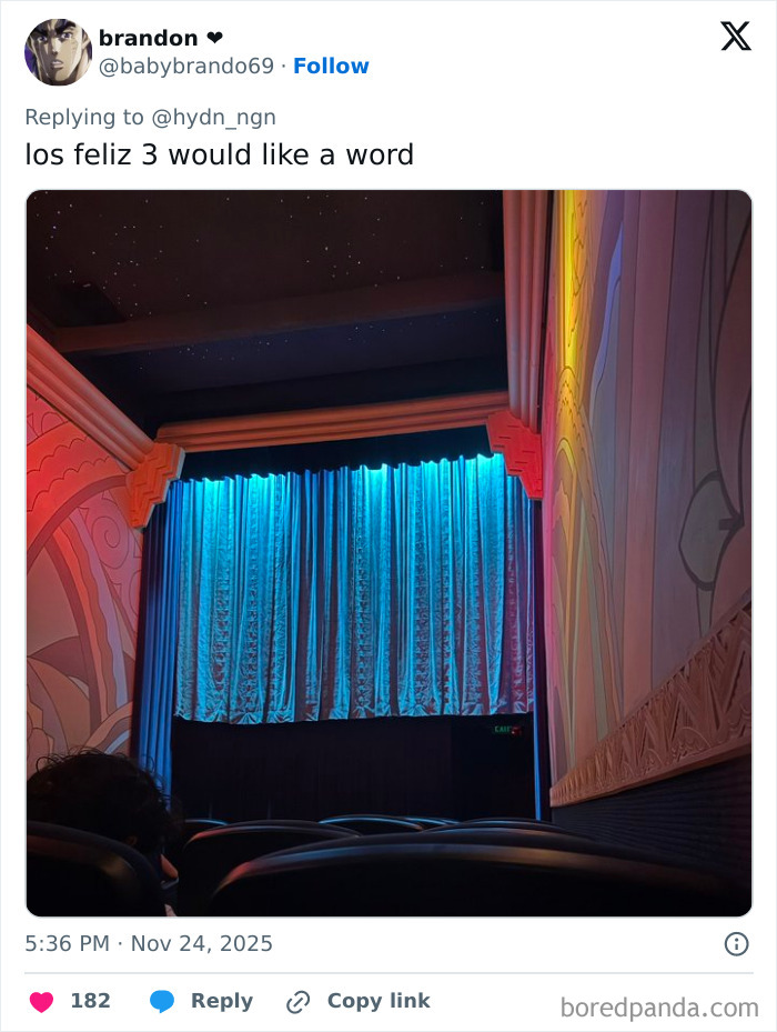 Interior view of a movie theater with blue curtains, colorful walls, and empty seats shared in worst movie theaters stories.