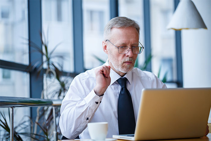 Man in office wearing glasses and tie, working on laptop while reacting to loud Christmas music nearby. Man in office wearing glasses and tie, working on laptop while reacting to loud Christmas music nearby.