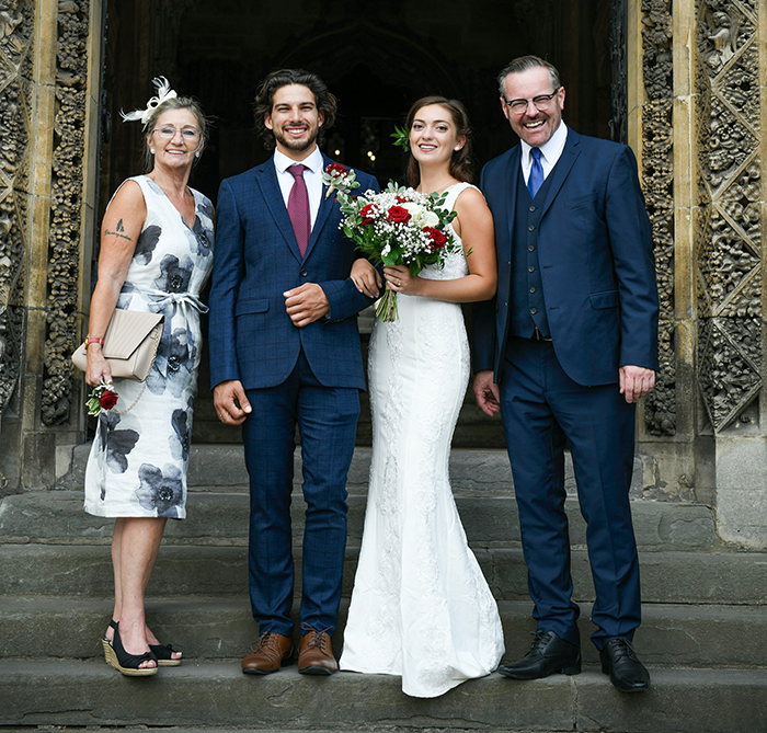 Bride and groom with family posing on wedding day, illustrating MIL&rsquo;s plan to affect bride&rsquo;s look in illustration backfires.