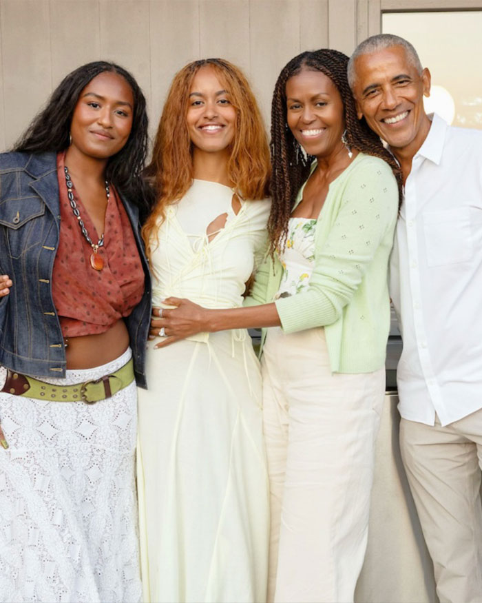 Michelle Obama and family smiling together, showcasing her bold new look praised by makeup artist.