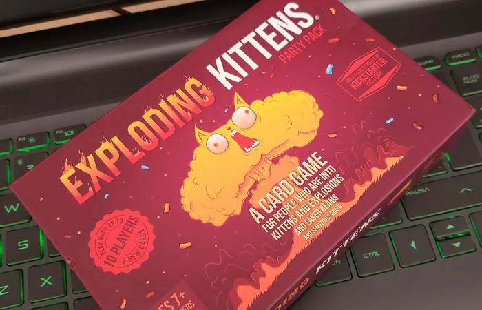 Exploding Kittens party pack card game box on a keyboard, a popular choice for the best party game keyword.