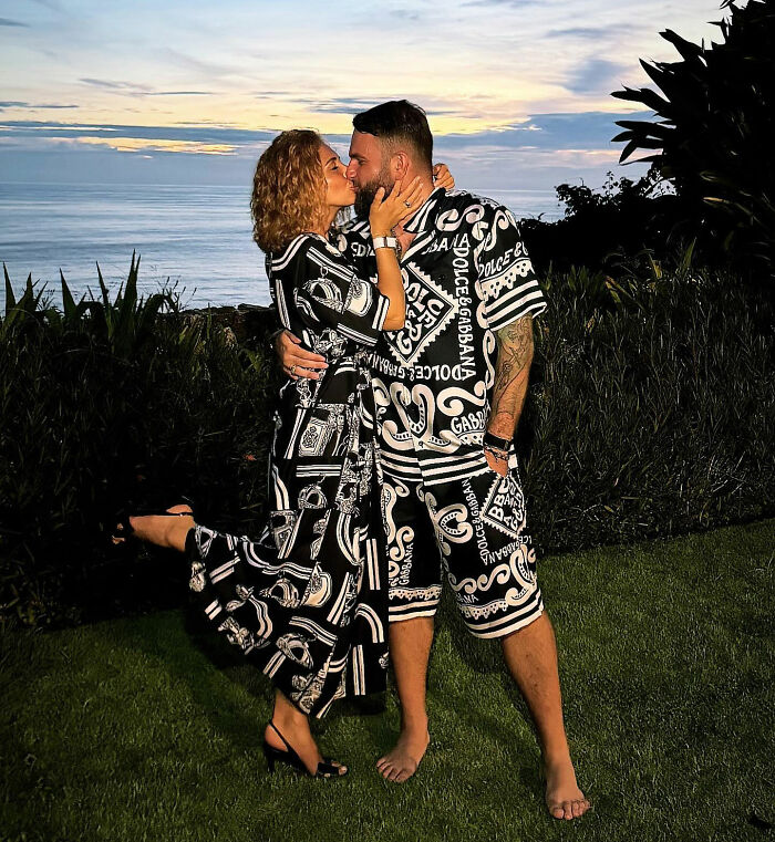 Couple in matching black and white outfits embracing outdoors near ocean at sunset, related to crypto scammer case. Couple in matching black and white outfits embracing outdoors near ocean at sunset, related to crypto scammer case.