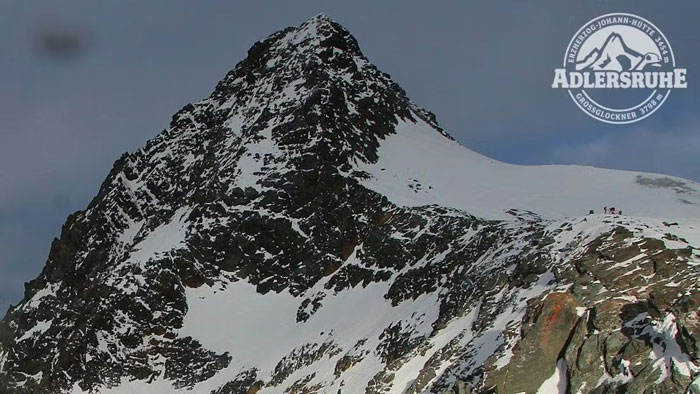 Snow-covered peak of Austria&rsquo;s highest mountain with hikers in distance, related to woman abandoned and fatally frozen case.
