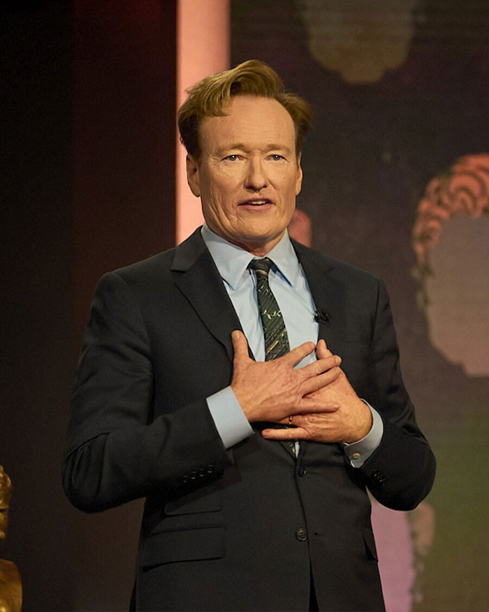 Man in a suit speaking on stage, with a focus on Rob Reiner and son Nick's fight before fatal incident. Man in a suit speaking on stage, with a focus on Rob Reiner and son Nick's fight before fatal incident.