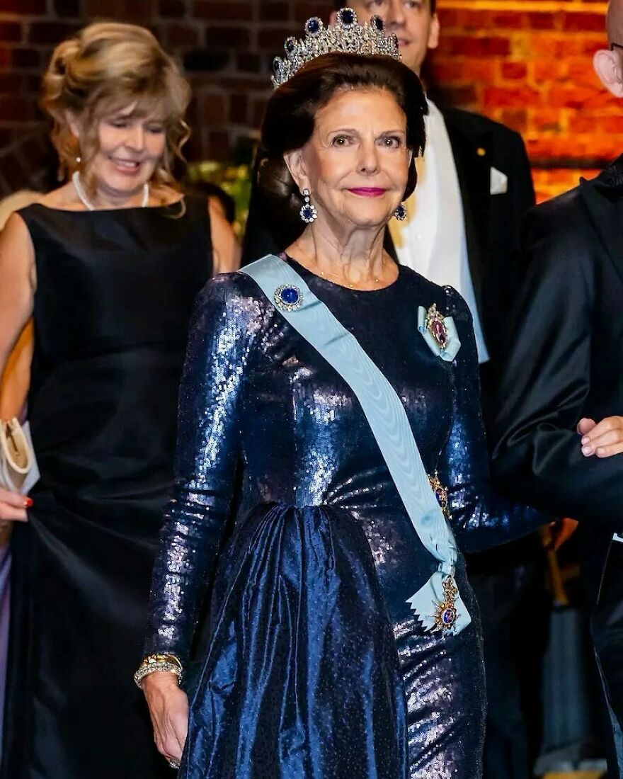 Queen wearing a jeweled tiara and blue sash at a formal event representing one of the oldest surviving monarchies.