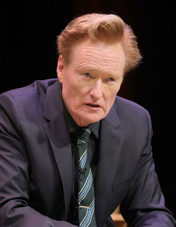 Conan O'Brien speaking in a dark suit and striped tie during a televised interview about celebrities and unusual questions. Conan O'Brien speaking in a dark suit and striped tie during a televised interview about celebrities and unusual questions.
