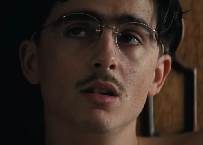Close-up of Timothée Chalamet wearing glasses, looking thoughtful during an interview amid arrogance criticism online. Close-up of Timothée Chalamet wearing glasses, looking thoughtful during an interview amid arrogance criticism online.