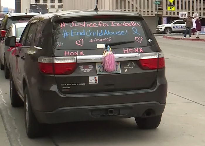 Black SUV with hashtags on rear window calling for justice and an end to child a***e in support of a slain child case.