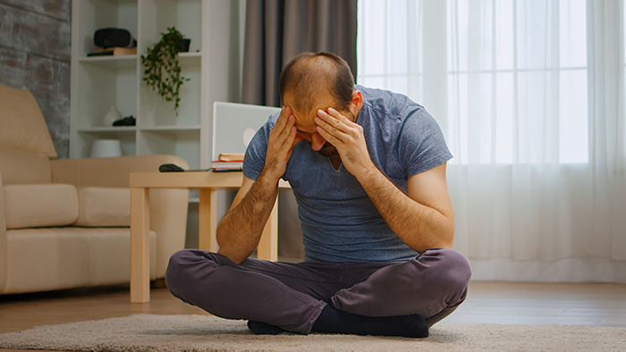 Man sitting on floor holding head in frustration, illustrating struggle with self-diagnosed autism behavior excuses.