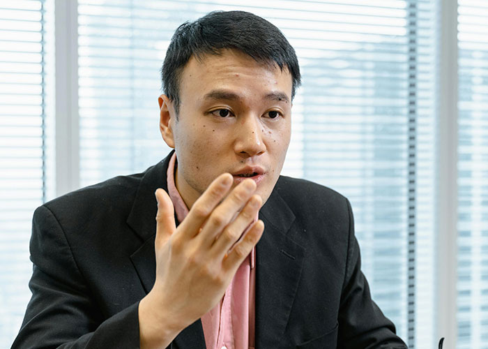Man taking a call in Korean, wearing a black suit, engaged in a serious conversation in an office setting. Man taking a call in Korean, wearing a black suit, engaged in a serious conversation in an office setting.