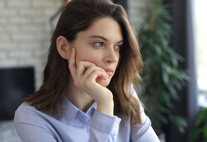 Woman looking thoughtful and concerned indoors, reflecting on boys nights at their house going too far.
