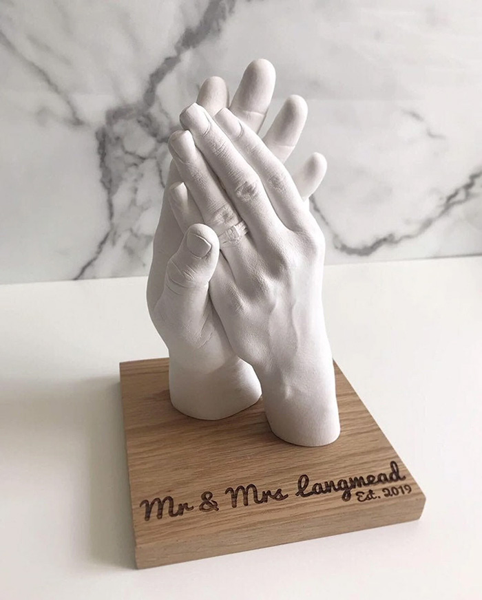 White sculpture of two hands clasped together on a wooden base, symbolizing at-home date night ideas for couples.
